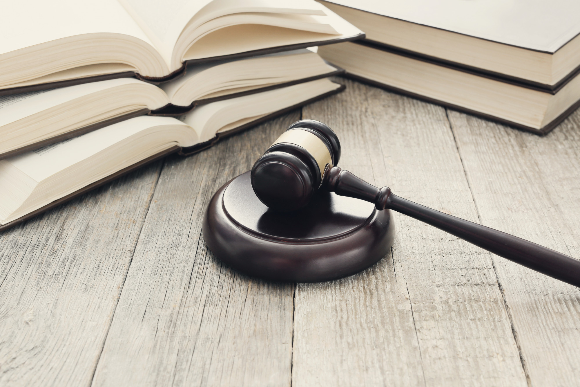 A judge's gavel sits on a wooden desk next to stacks of legal books.