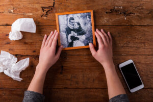 A woman holds a broken picture of her and her husband.