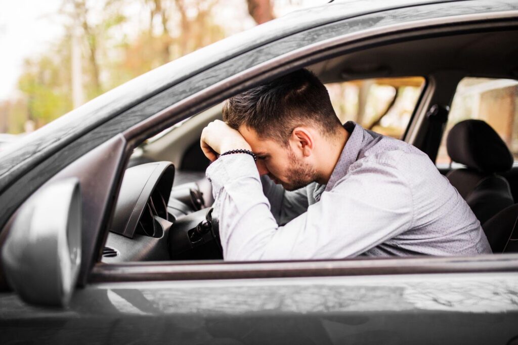 Exhausted driver yawning at the wheel, struggling to keep eyes open on a big highway.