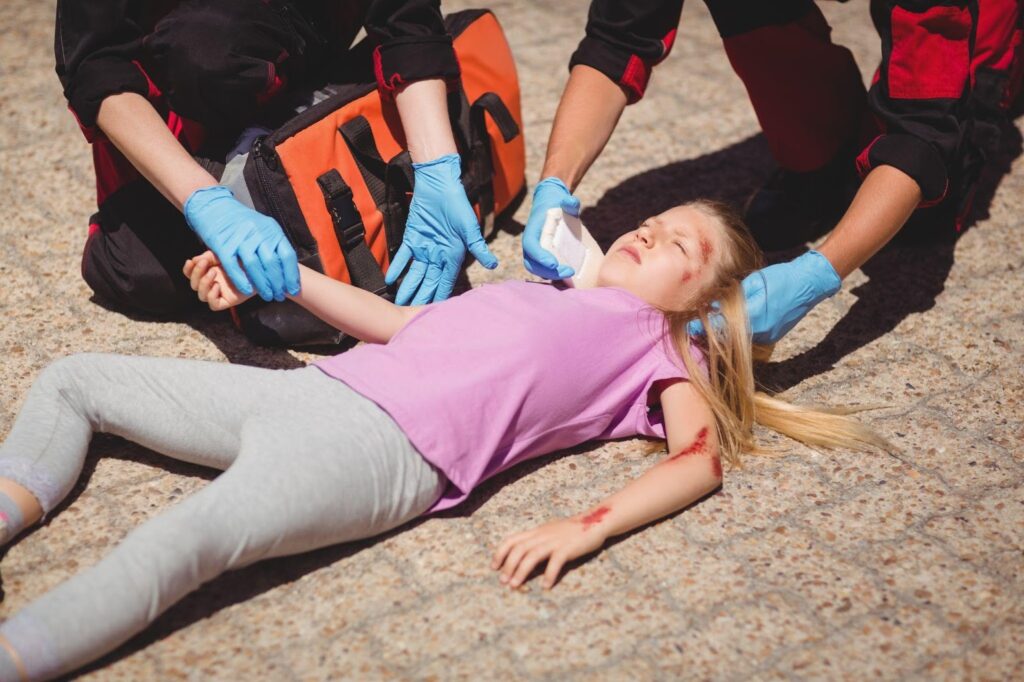 Young child with minor head injury being treated by paramedics on the street.