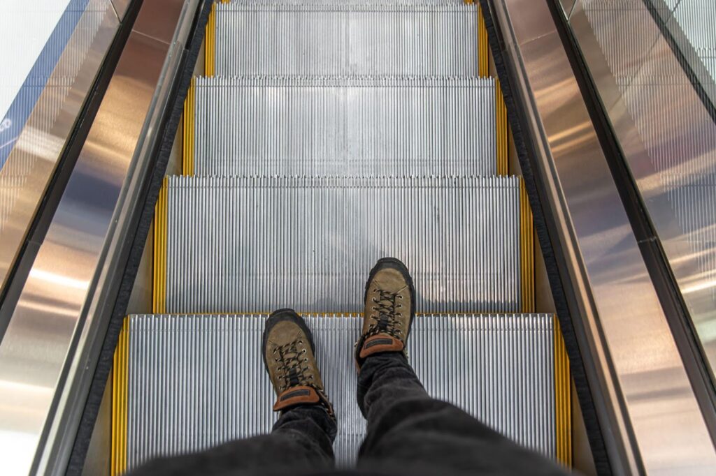 Person cautiously descending on a malfunctioning escalator, illustrating potential slip and fall hazards.