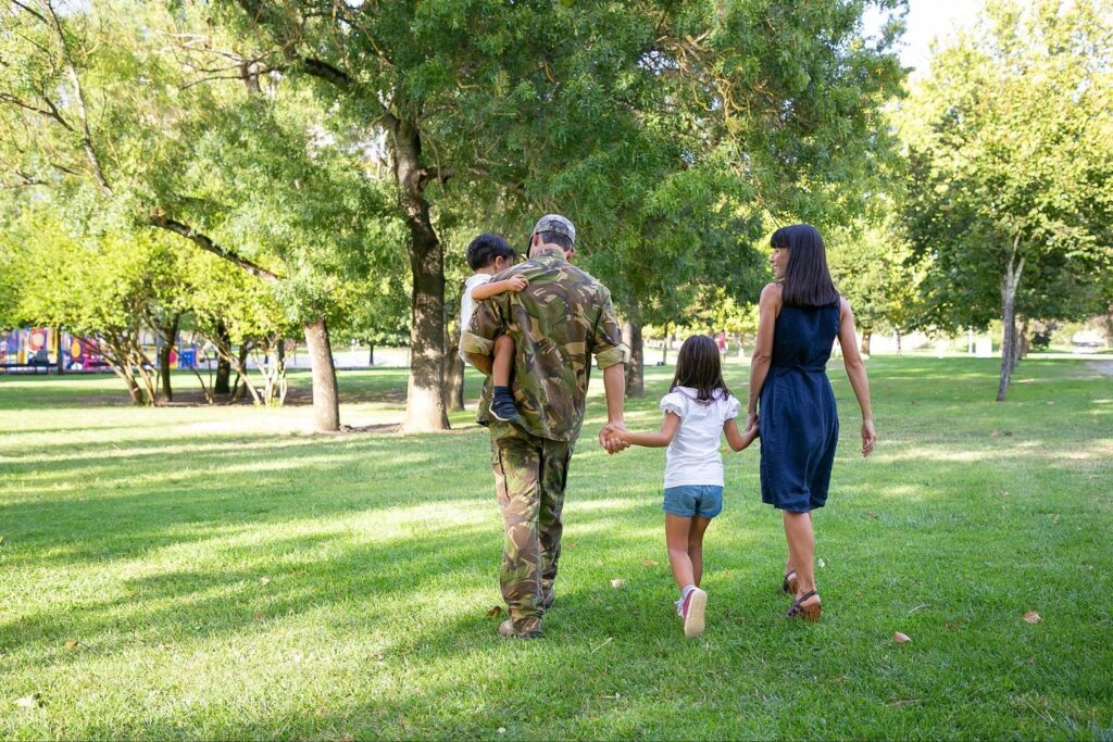 Smiling veteran in uniform embracing spouse and children, representing support for military families.