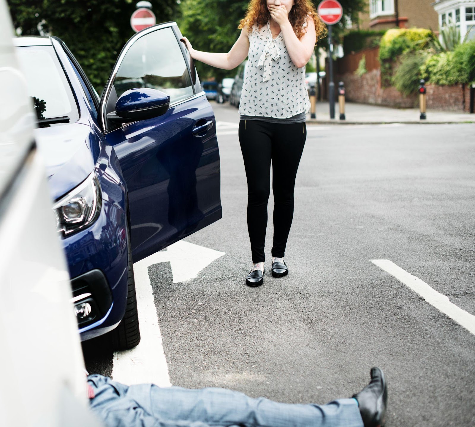 Pedestrian lying on the ground after an accident, with concerned bystanders nearby.