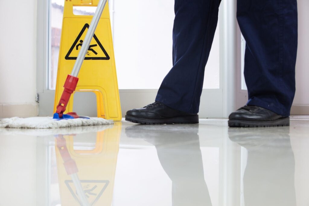 Yellow caution sign warning of wet floor in a busy retail aisle.