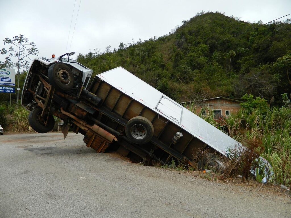 Side view of a crushed truck on the roadside, severely damaged and lying on its side after an accident.