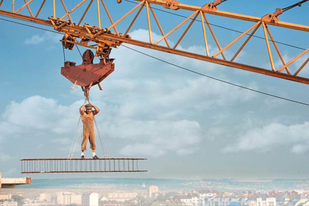 A construction worker operates at a height on a crane, emphasizing the potential risks associated with crane accidents.