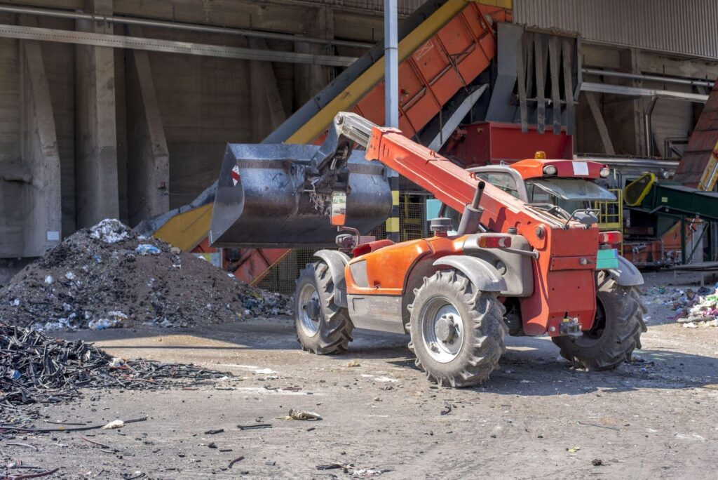 Construction trucks are positioned at a demolition site, with debris and dust surrounding them.