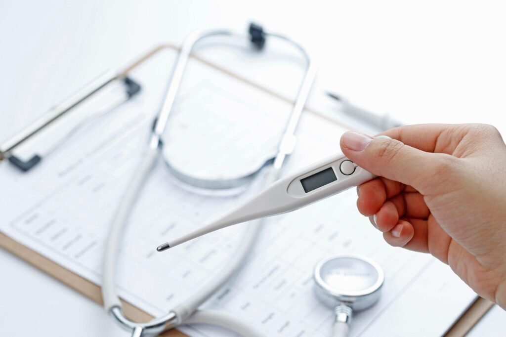 A hand holds a thermometer, with a stethoscope visible in the background, symbolizing a medical examination setting. The image highlights the importance of accurate diagnosis, underscoring the risks of misdiagnosis in medical malpractice cases.