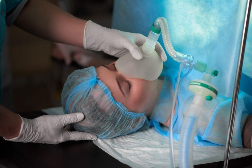 A patient lies on an operating table receiving anesthesia, with medical equipment and monitors surrounding them. The image highlights the critical nature of anesthesia administration and the potential risks of anesthesia errors in surgical settings.