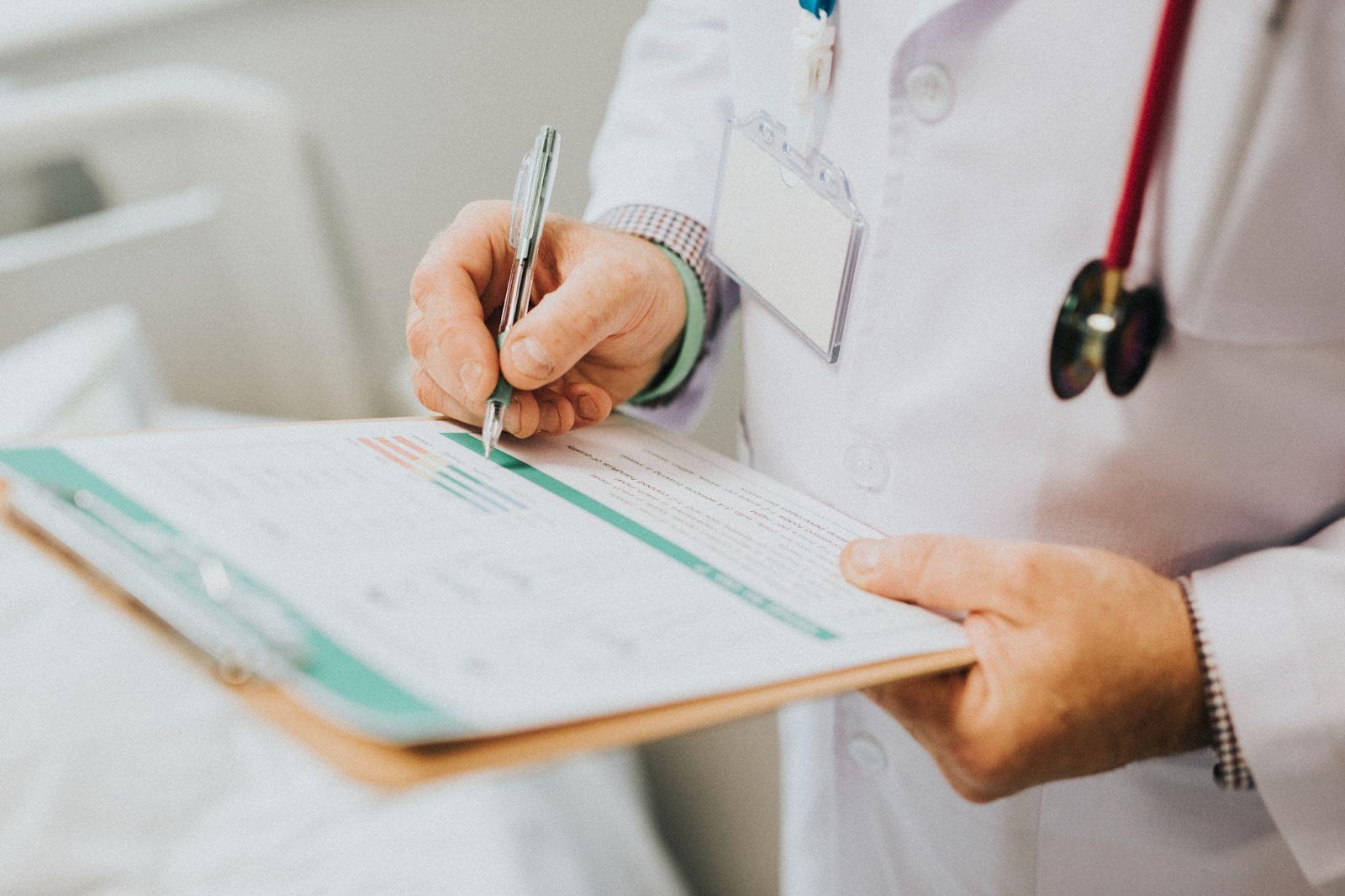 A doctor in a white coat, focused on writing a diagnosis on a clipboard, with medical equipment visible in the background.