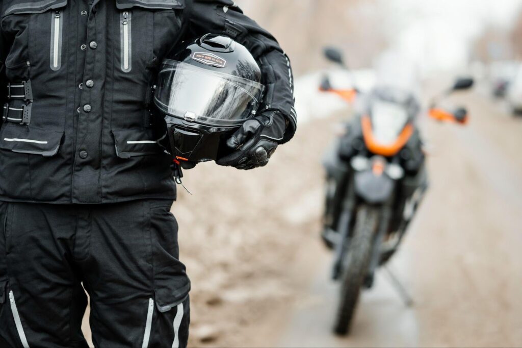 Close-up of a biker holding a helmet, highlighting the importance of adhering to motorcycle helmet laws.