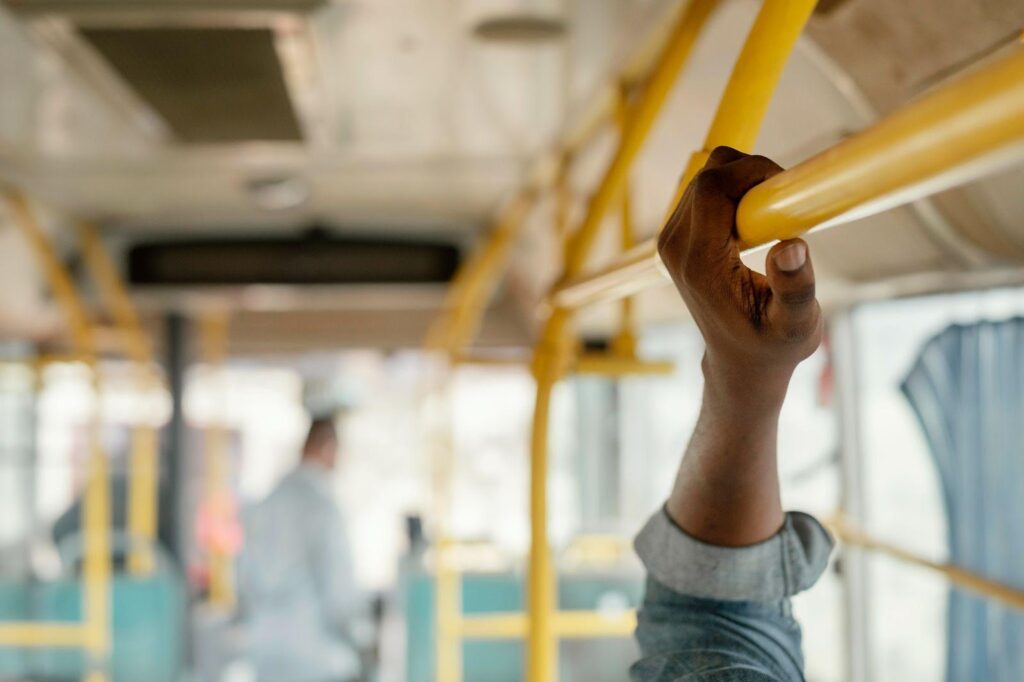 A hand gripping a pole inside public transportation, emphasizing the need for safety and stability to prevent accidents while commuting.