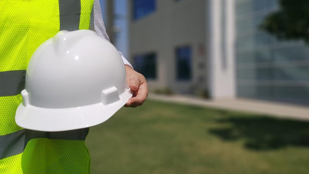 Construction worker in safety vest holding a hard hat.