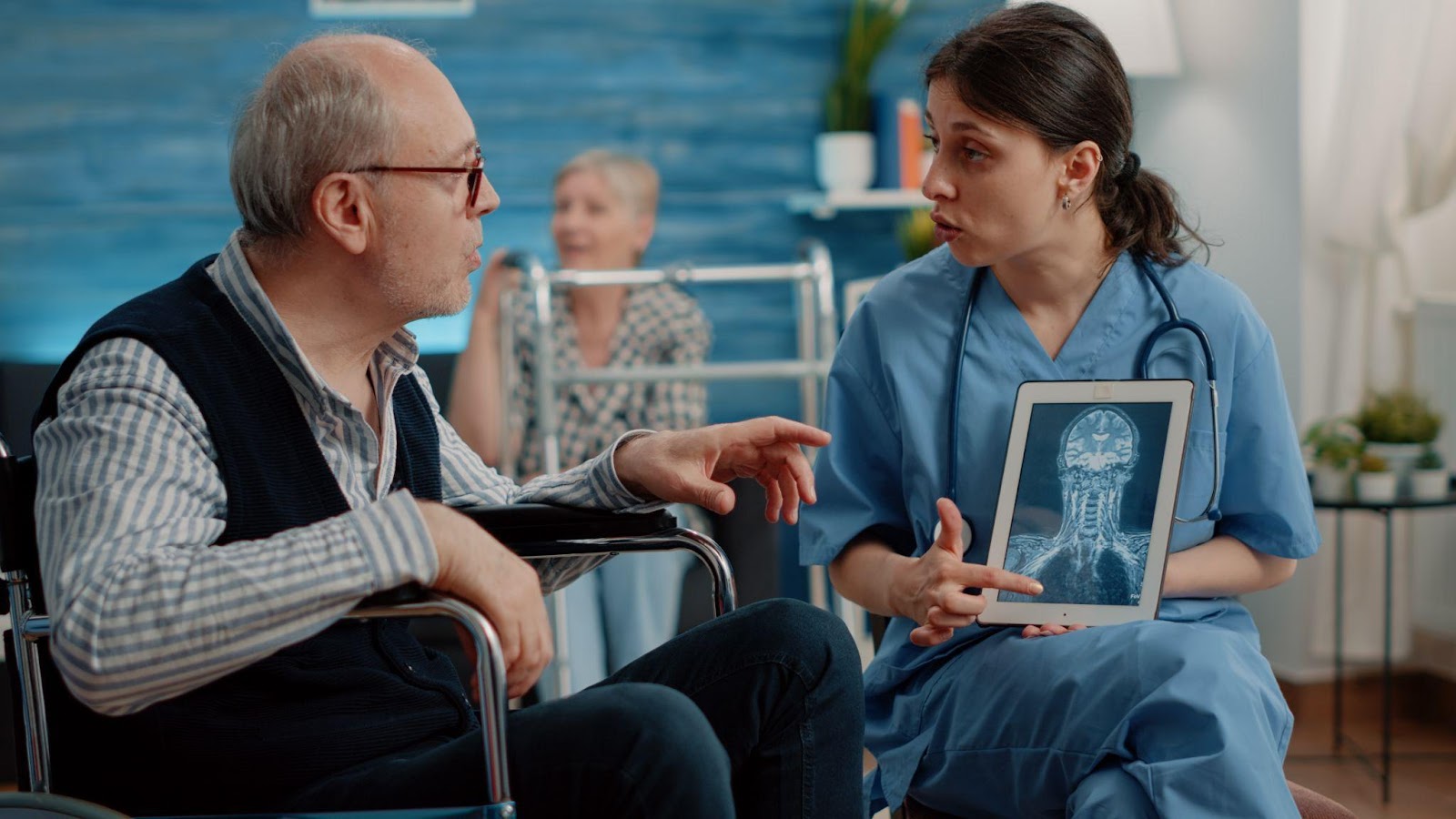 A doctor shows a patient a brain scan on a tablet, explaining details about a brain injury, with the scan highlighting affected areas.