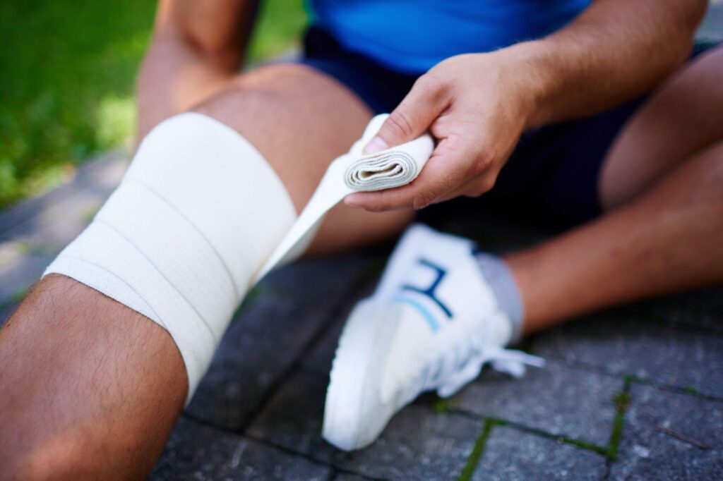 A person with a bandaged knee sitting outdoors, symbolizing recovery after an injury. This image relates to comparative negligence, highlighting the differences between contributory and comparative fault systems in determining liability for personal injury cases.