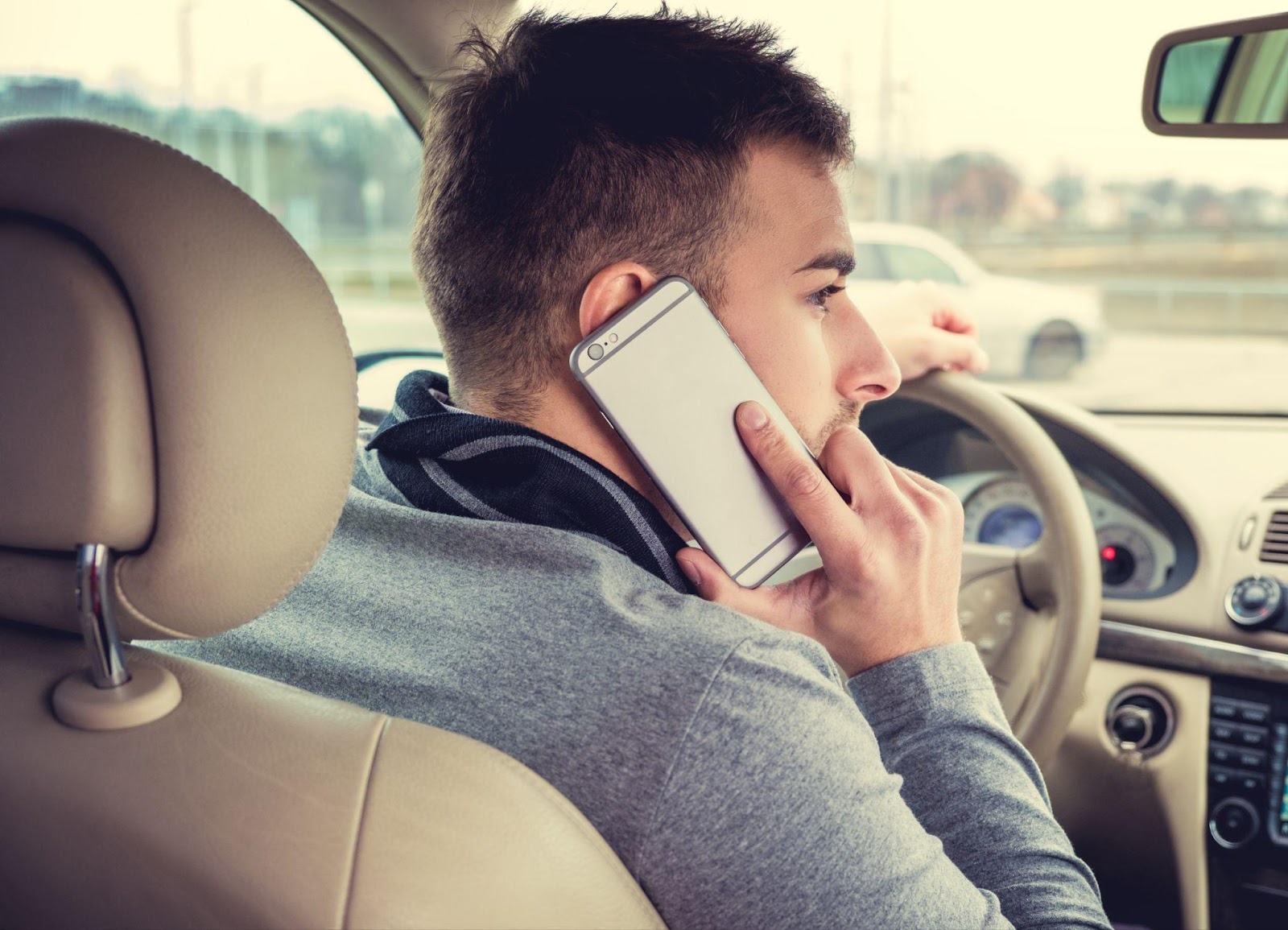 A driver using a mobile phone while behind the wheel, highlighting the dangers of distracted driving and the importance of understanding texting and cell phone use laws in Alabama.