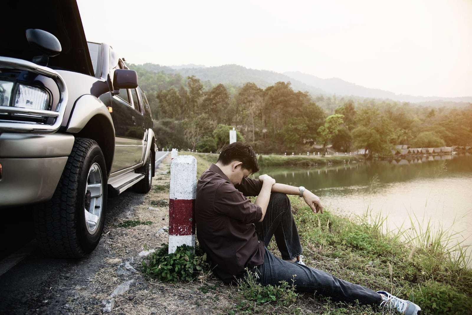 A drunk driver sitting beside his crushed car after a crash, with visible signs of alcohol-related impairment. The scene highlights the serious consequences of drunk driving accidents, including alcohol-related injuries and fatalities.