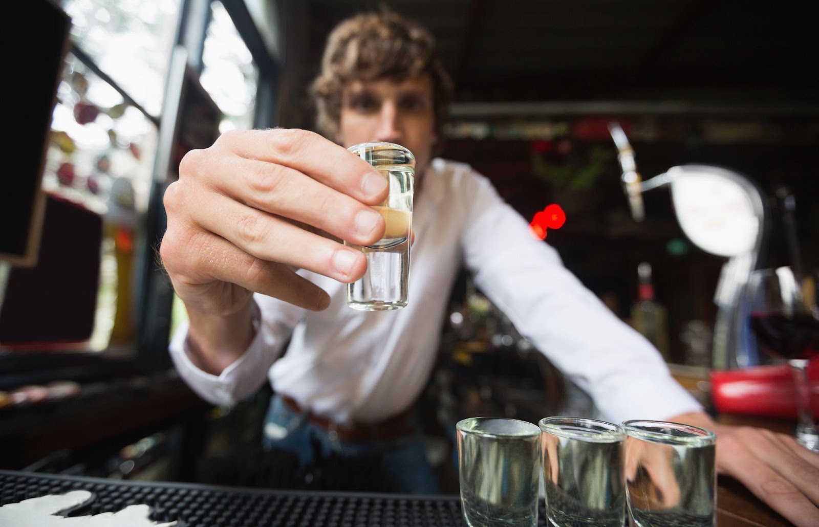 A bartender serving shots at a bar, symbolizing dram shop liability and social host responsibility in preventing drunk driving accidents.