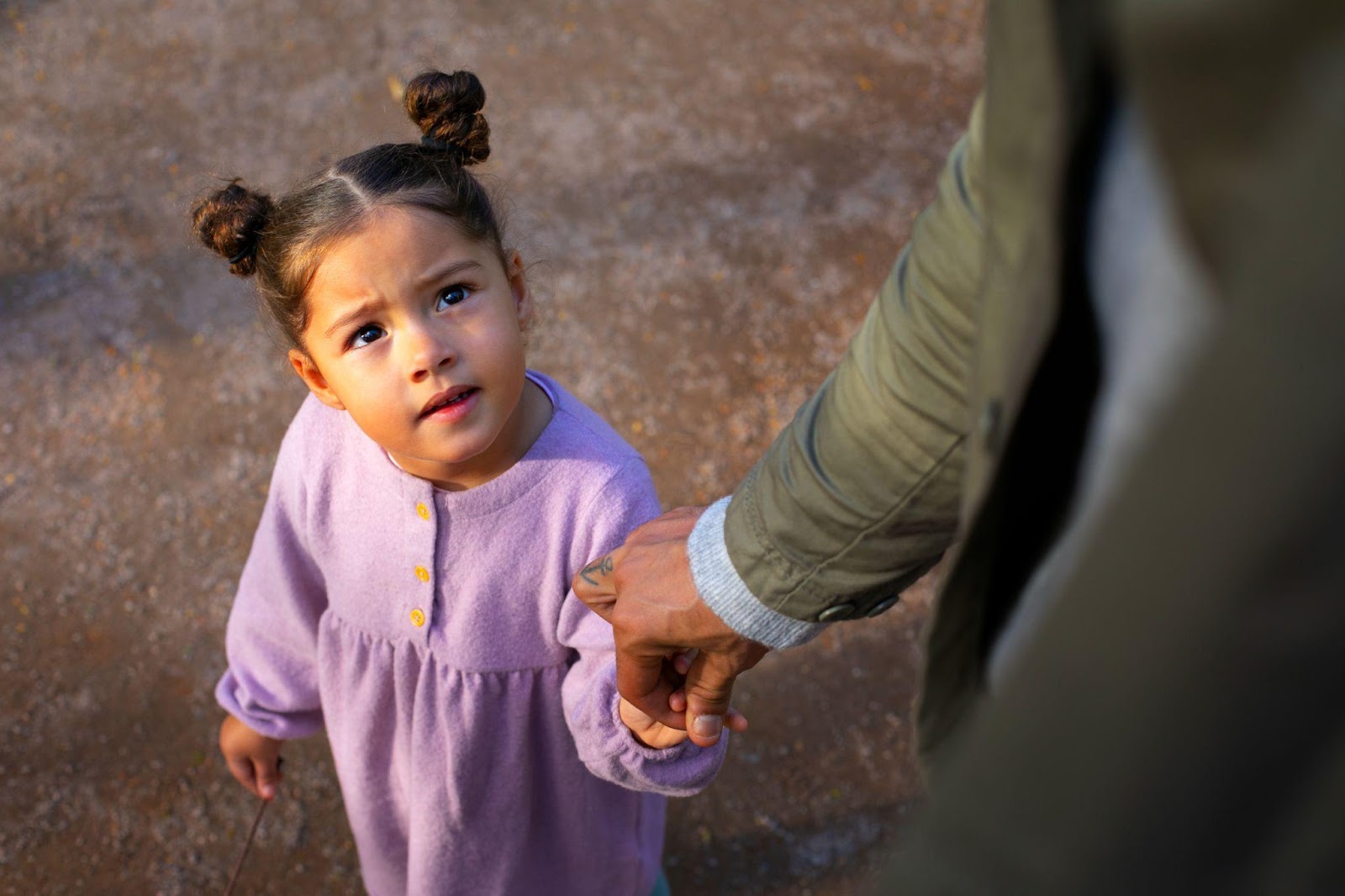 A child holding hands with their father, symbolizing the responsibility of providing care and support. This image relates to enforcing child support orders in Alabama, emphasizing the importance of ensuring financial support for the well-being of children.