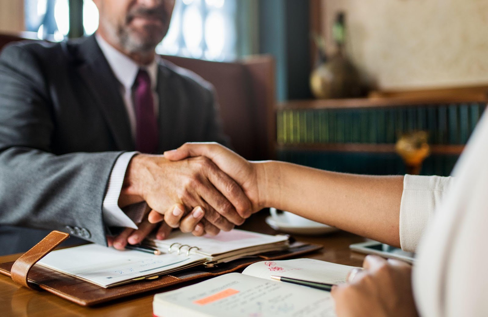 A lawyer shaking hands with a client in an office, symbolizing trust and professional guidance. This image relates to the statute of limitations, focusing on exceptions and tolling circumstances that can affect the timeline for filing a legal claim.