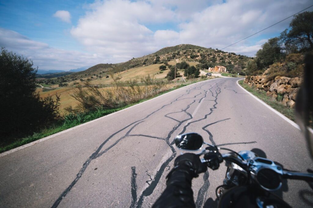 Close-up of a motorcycle in the front view, navigating a road with lane splitting. The image highlights the potential risks associated with this maneuver, such as accidents involving other vehicles or riders.