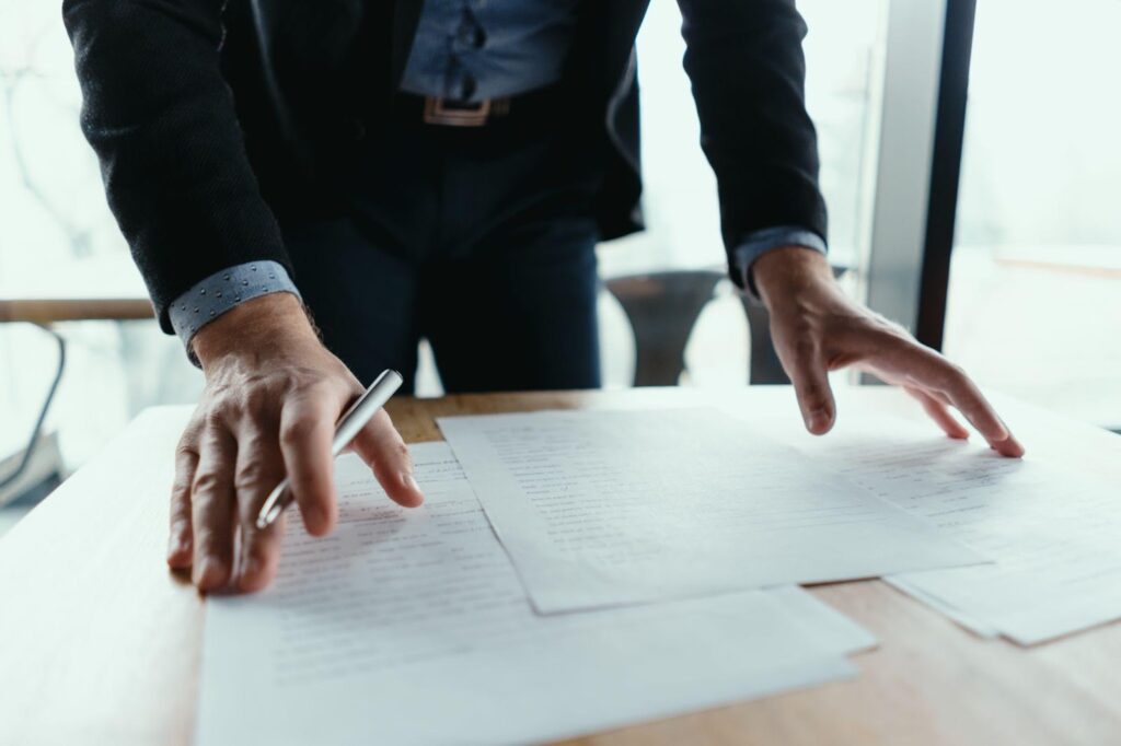 A lawyer standing over a desk, reviewing papers with a focused expression. This image relates to the statute of limitations and the importance of understanding time limits for filing personal injury lawsuits to ensure legal rights are preserved.