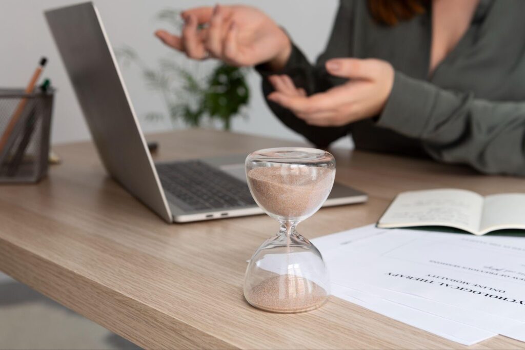 A lawyer talking to a client with a sand timer on the desk, symbolizing the urgency of legal deadlines.