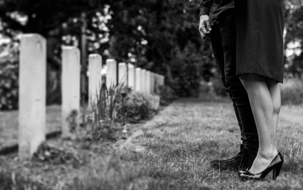 A grieving couple stands together in a cemetery, holding each other for support. The image reflects the emotional impact of wrongful death claims, highlighting the pursuit of justice and accountability for a loved one's loss due to negligence.