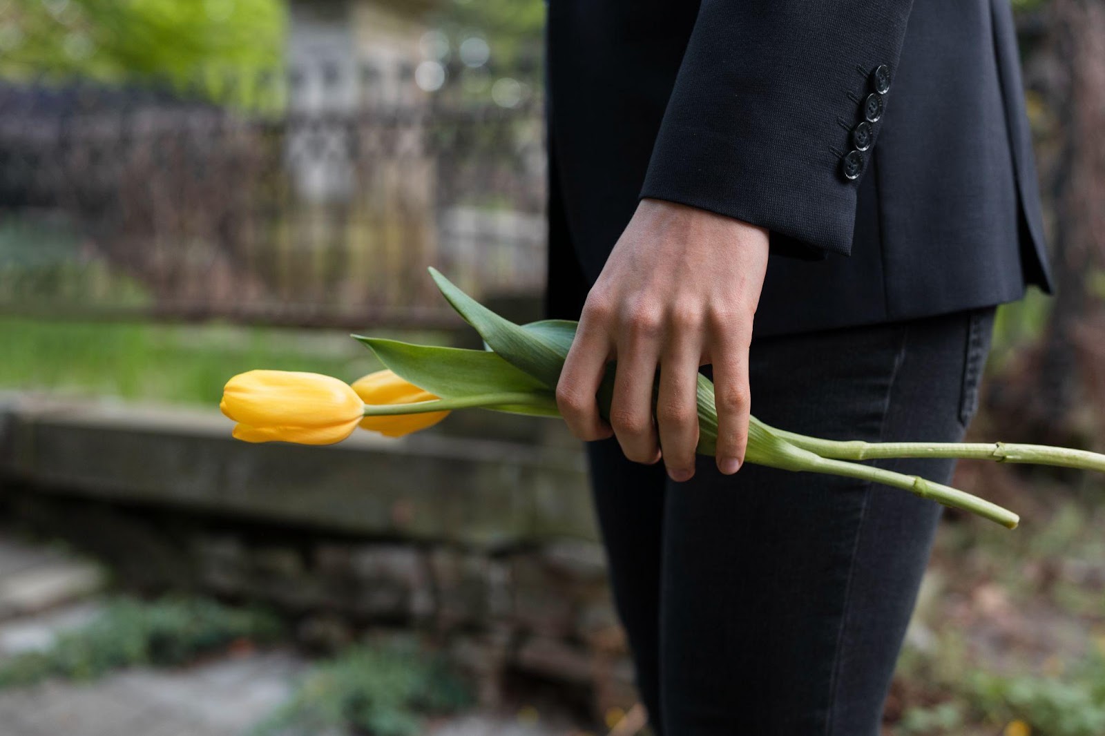 A person stands in a cemetery holding a flower, symbolizing mourning. The image reflects the somber reality of wrongful death claims, underscoring the legal pursuit of justice for a loved one's untimely passing due to negligence.