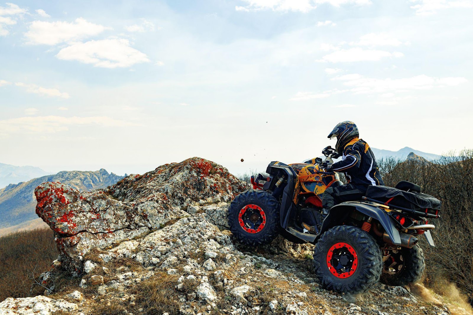 A person wearing a helmet rides an all-terrain vehicle (ATV) on rugged mountainous terrain, emphasizing the importance of safety gear and precautions. Following ATV safety tips, such as wearing proper protective equipment, understanding terrain risks, and operating responsibly, can significantly reduce the likelihood of injuries.