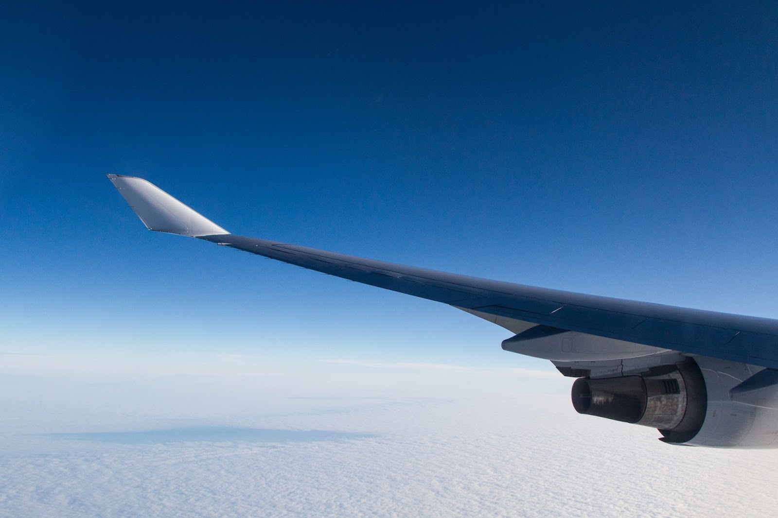 View from an airplane window showing the aircraft's wing and clouds below, symbolizing the complexity of aviation accidents, including investigations, liability, and lawsuits, particularly in Alabama.