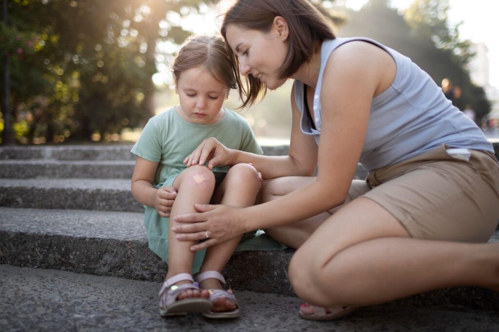 A mother tending to her child's injured knee on the side of a road, symbolizing care after an accident. This image relates to child injury claims, emphasizing the legal rights and compensation available for minors injured due to negligence.