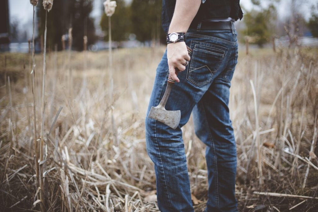 A person holding an axe while working on a farm, surrounded by wild crops, symbolizing the labor-intensive nature of agriculture. This image relates to farming and agricultural accidents, highlighting injury risks and the compensation options available for workers in such environments.