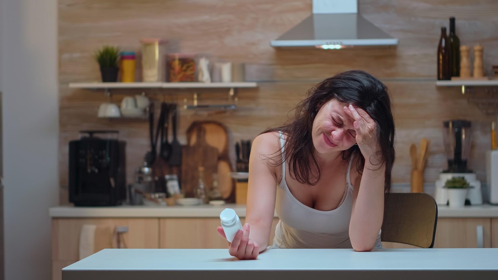 A woman sitting at a table holding pills, appearing unwell, symbolizing the effects of foodborne illness. This image relates to foodborne illness and contamination, emphasizing issues of liability and the potential for compensation in cases of negligence.