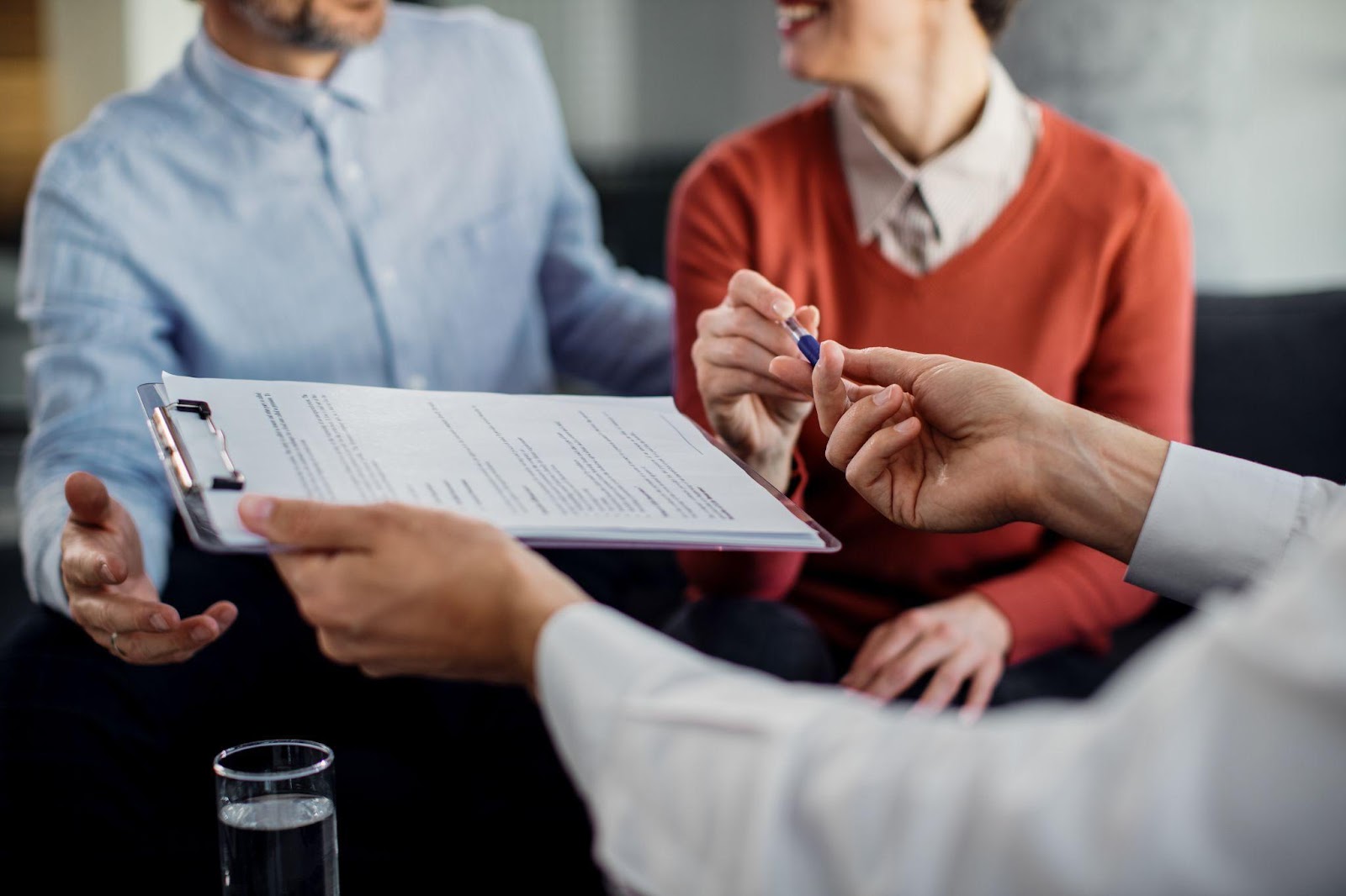 A couple sitting with an insurance agent, preparing to sign papers, symbolizing agreement and understanding. This image relates to insurance coverage, focusing on subrogation and reimbursement rights, which outline the insurer's ability to recover costs from third parties after paying a claim.