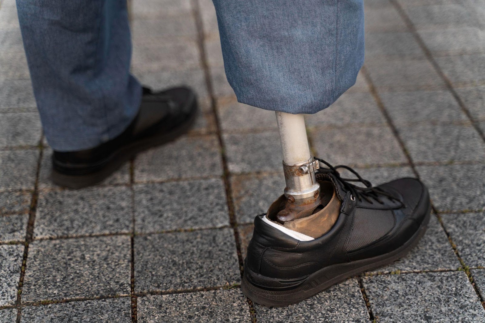 Close-up view of an individual with a prosthetic leg, standing on a paved surface. This image symbolizes the journey of recovery and adaptation after a traumatic amputation, focusing on topics such as rehabilitation, the use of prosthetics, and the pursuit of rightful compensation.