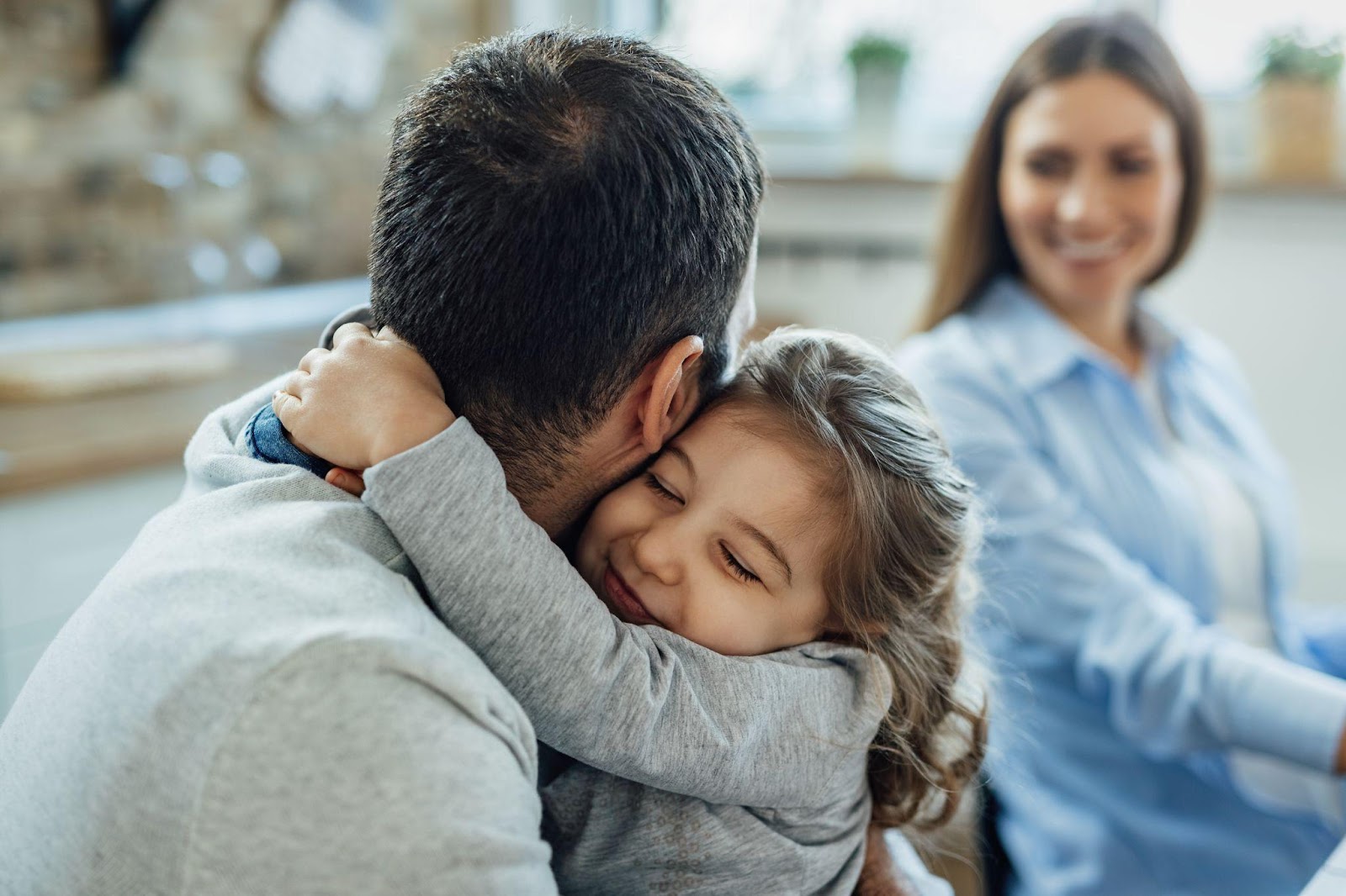 A family with a child hanging onto one parent's arm, symbolizing love and support, with a focus on FAQs about adoption in Alabama. The image highlights the importance of understanding the adoption process and what families need to know when considering adoption in Alabama.