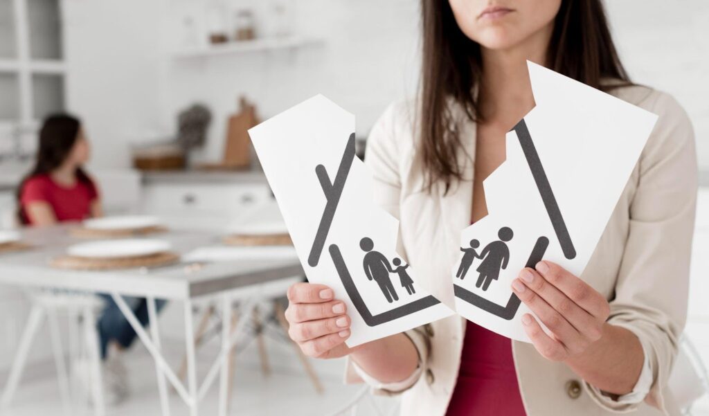 Close-up of a woman holding a torn family illustration, symbolizing the complexities of property division in Alabama divorces, with a child visible in the background.