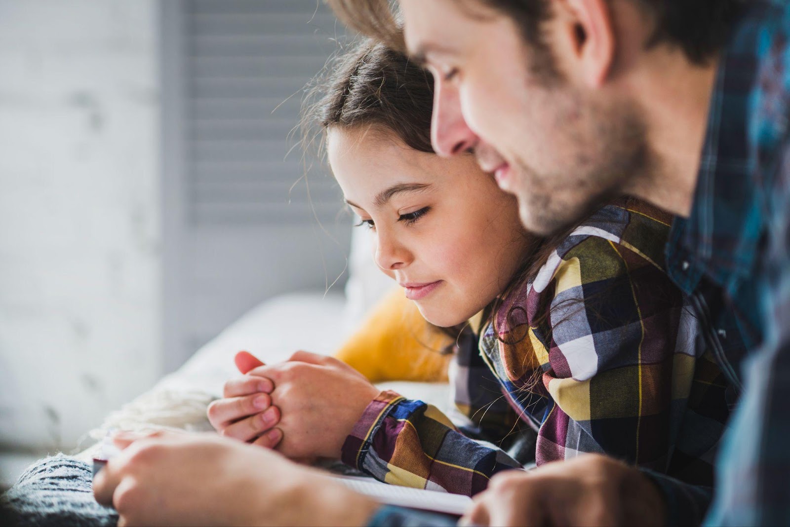 A father and daughter share a tender moment while reading together, symbolizing the importance of child support modifications in Alabama to ensure children's needs are met.