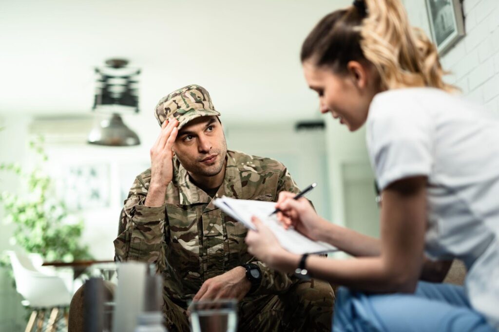 A military service member in uniform discusses important matters with a female professional holding a clipboard, representing the complexities of military divorce in Alabama.