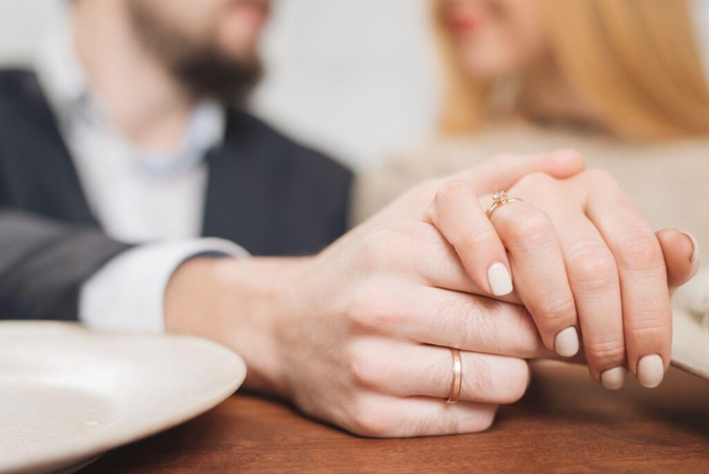 A close-up of a married couple's hands, wearing wedding rings, gently touching. The image relates to FAQs about prenuptial agreements in Alabama, symbolizing marriage and legal planning.