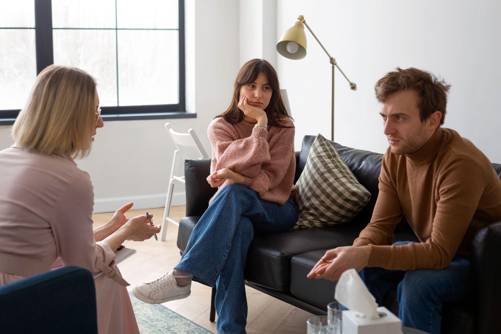 A couple sitting with a mediator at a table, engaged in discussion, symbolizing conflict resolution. This image relates to the role of mediation in Alabama child custody disputes, focusing on facilitating communication and finding mutually agreeable solutions.