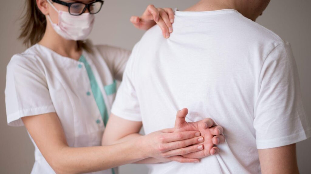 A woman wearing a mask and checking a patient, symbolizing medical care and rehabilitation. This image relates to spinal cord injuries, emphasizing rehabilitation, adaptive equipment, and lifestyle changes for improving quality of life.