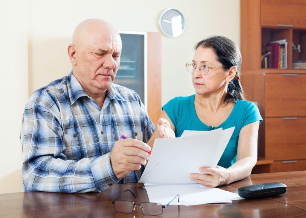 A grandparent couple filling out legal documents, symbolizing the process of filing for grandparents' rights in Alabama.