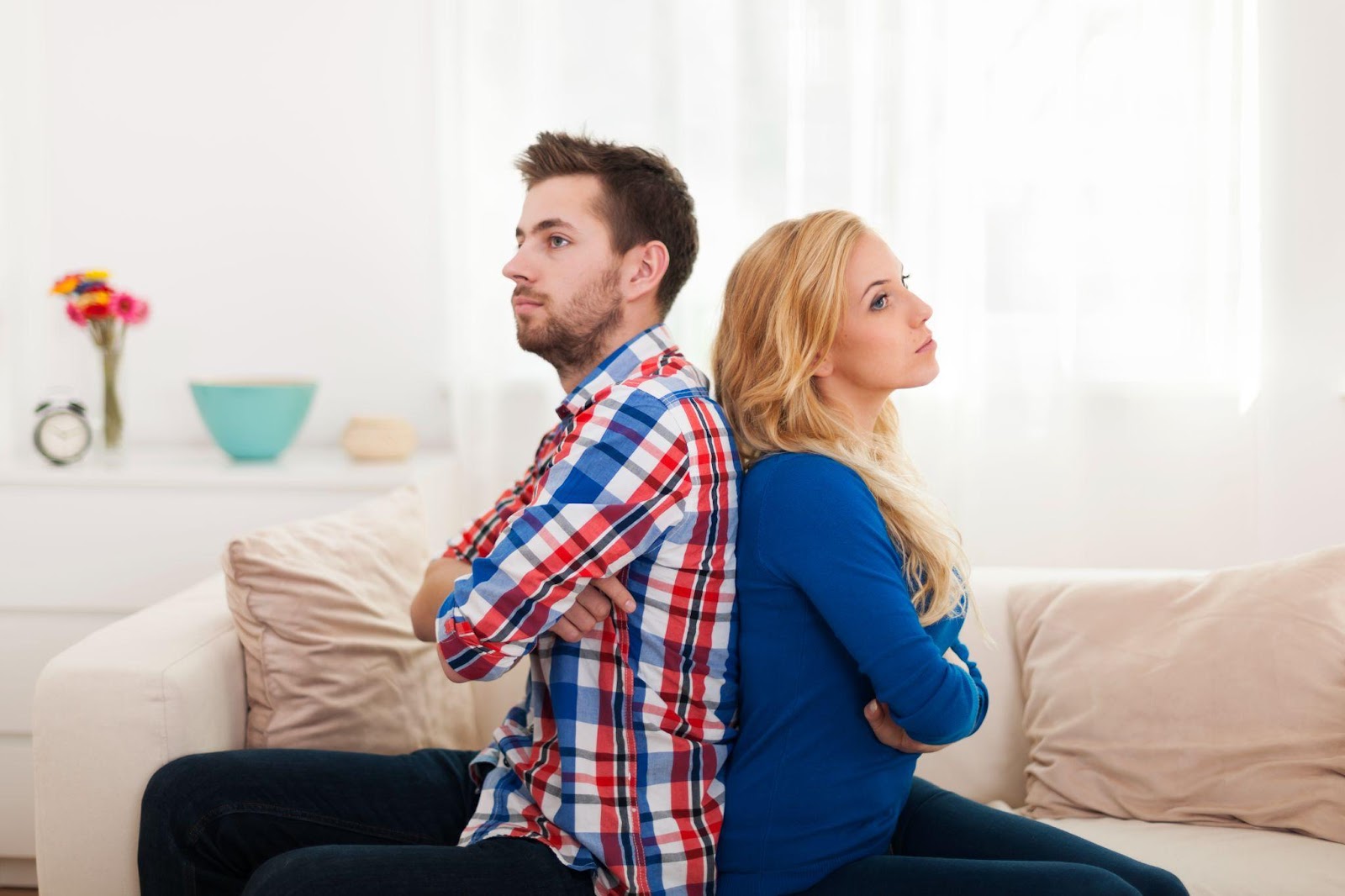 A couple sitting back to back, reflecting the emotional distance and the question of how long a divorce takes in Alabama.