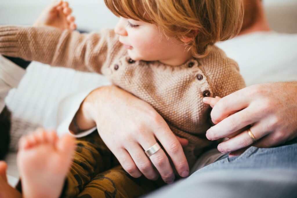 A child cradled in their parent's hands, symbolizing the emotional and financial commitment involved in the adoption process in Alabama.