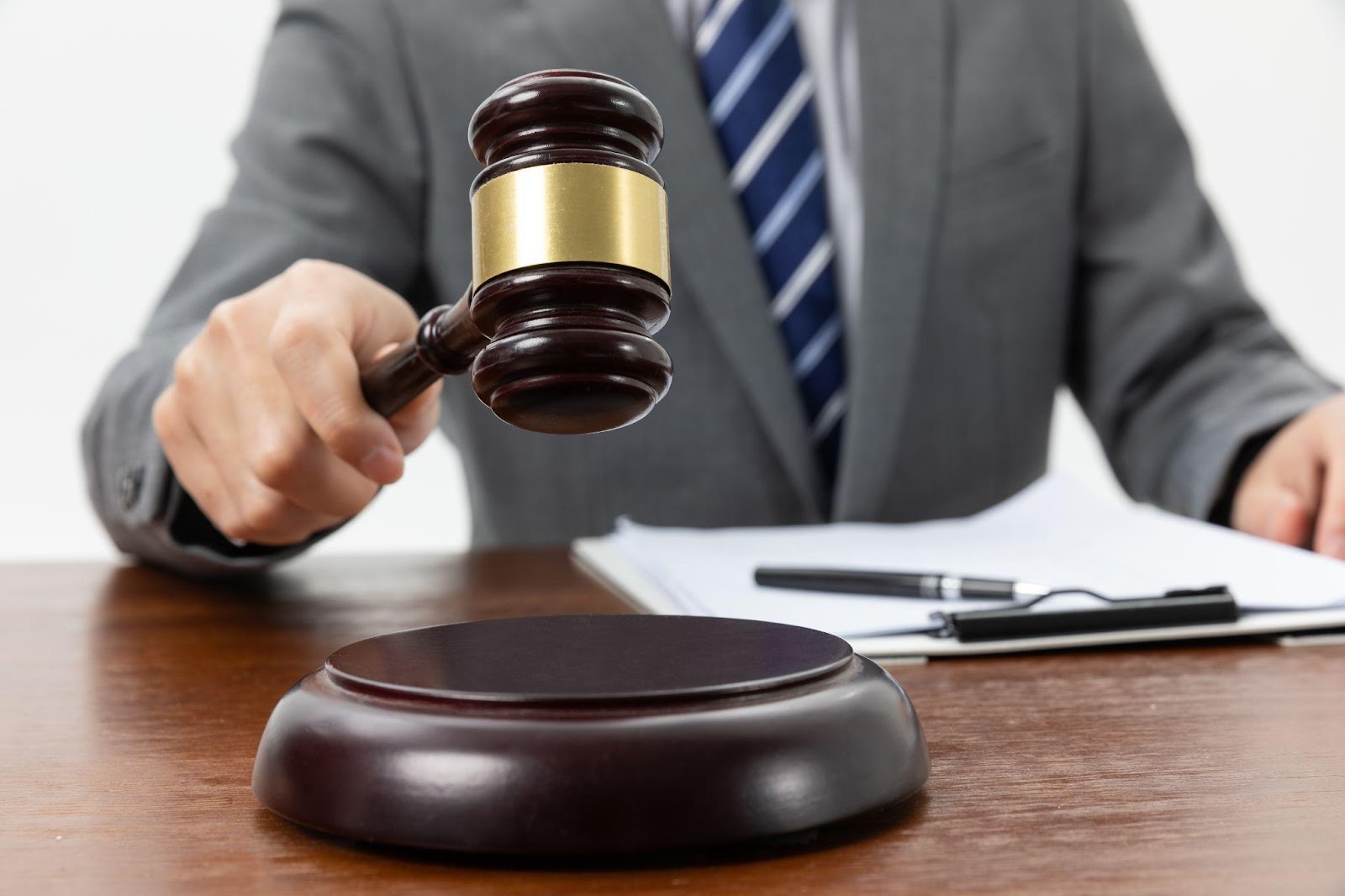 Closeup shot of a person holding a gavel on a table, symbolizing the process of filing a civil lawsuit in Alabama.