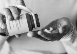 Close-up of a woman's hand pouring pills from a bottle into her palm, emphasizing the importance of awareness around drug interactions and safe medication practices.