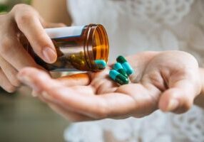 Close-up of a hand holding various medication pills, symbolizing concerns about dangerous drugs and the importance of awareness around drug recalls for consumer safety.