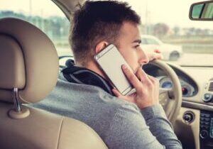 A driver using a mobile phone while behind the wheel, highlighting the dangers of distracted driving and the importance of understanding texting and cell phone use laws in Alabama.